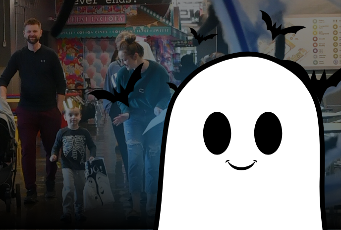 A cheerful cartoon ghost with bats flying around, overlaying a festive indoor Halloween scene with families and decorations.