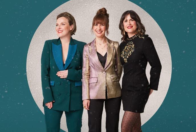 Three members of the band The Good Lovelies smiling and posing in elegant, shimmering outfits.