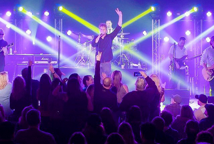 The band of Grace, performing on stage in front of a crowd in purple light.