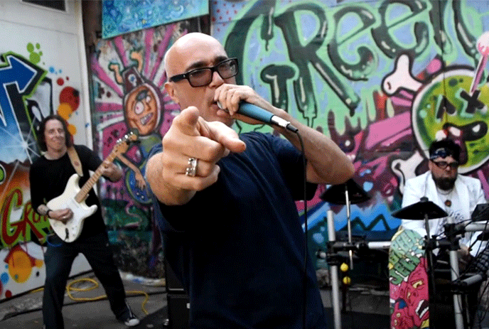 Green Jelly performing against a graffiti covered wall.