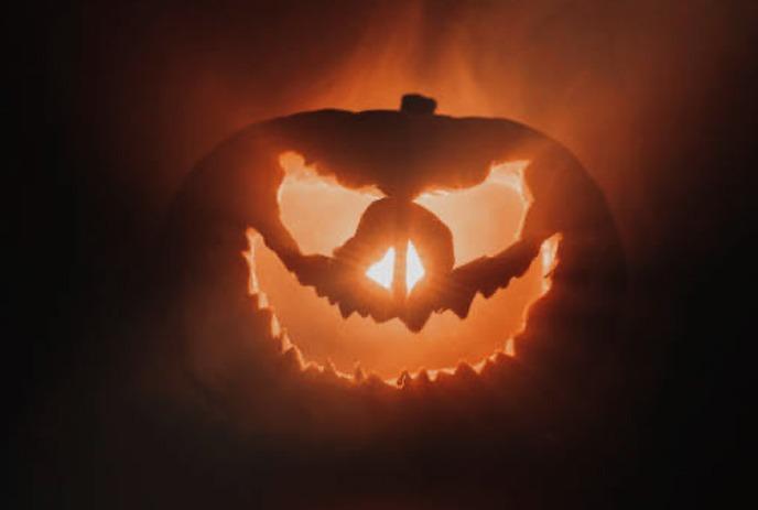 Black silhouettes of bat, ghost, cauldron, spider, hat with hanging webs creating a spooky Halloween scene.
