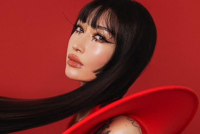 Close-up picture of Marie Vaunt with sleek dark hair, and vivid red backdrop.