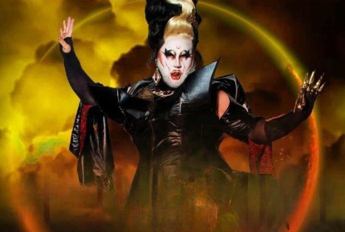 Drag Queen in black costume under a fiery dramatic sky.