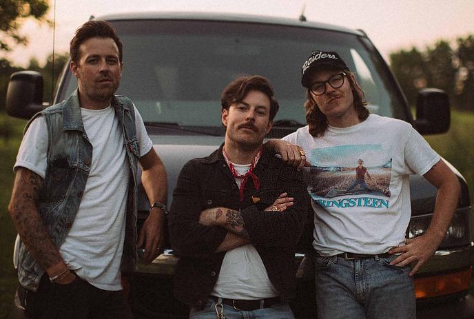 Members of the band Honest Heart Collective posing by a truck outdoors