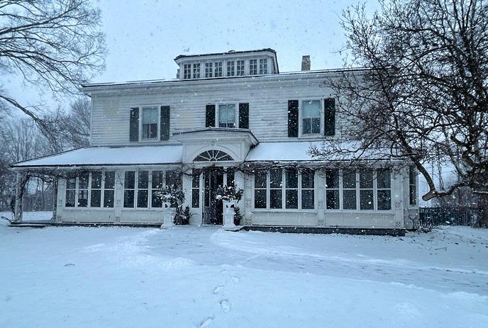 Eldon House covered in snow, with the camera facing the front of the house and its garden.