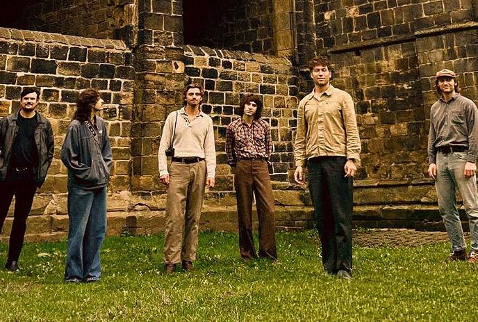 Four artists standing on a road, looking up at the camera in a casual outdoor group portrait.