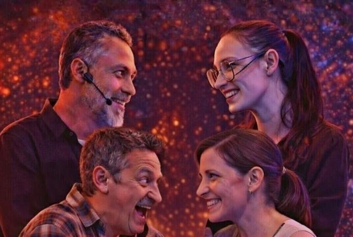 Four people stand closely together, smiling warmly at each other against a vibrant, starry background.