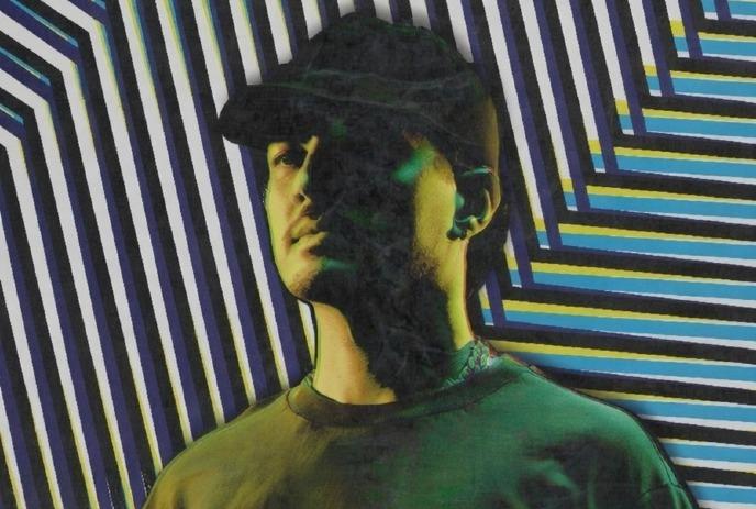 A colourful portrait of OMNOM wearing a hat, in front of a striped pattern background.