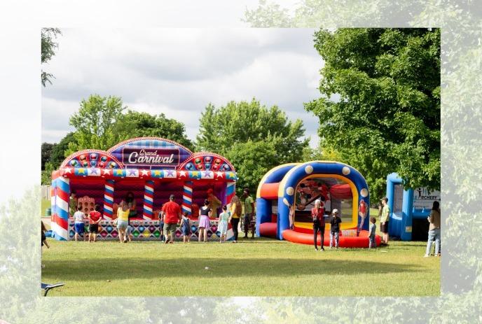 Bouncy castle and carnival games being enjoyed by families outdoors.