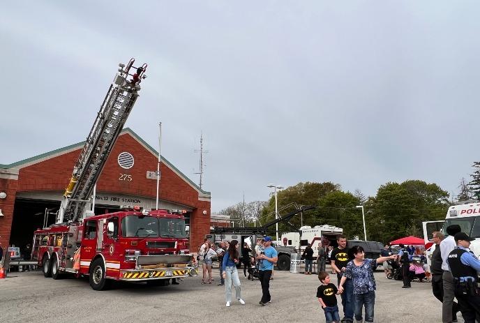 Families gather outside a fire station to explore emergency vehicles and engage with first responders.