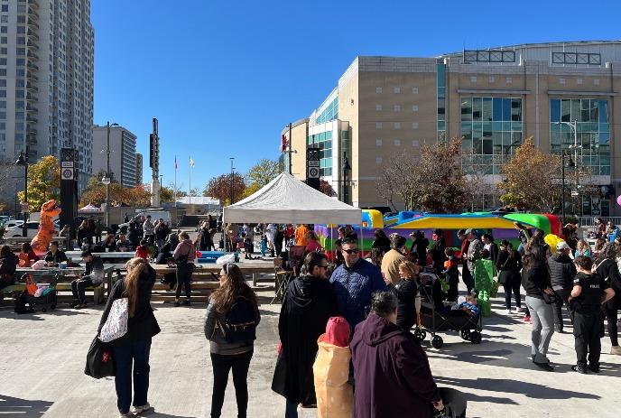 Families and visitors enjoying Downtown Candy Crawl in a downtown area, on a sunny day.