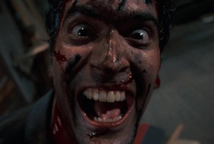 A close-up picture of a man screaming with wide open mouth under a dark background.