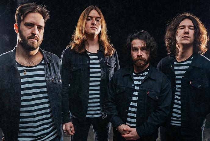 Four people in matching striped shirts and black jackets posing together before graphic backdrop.