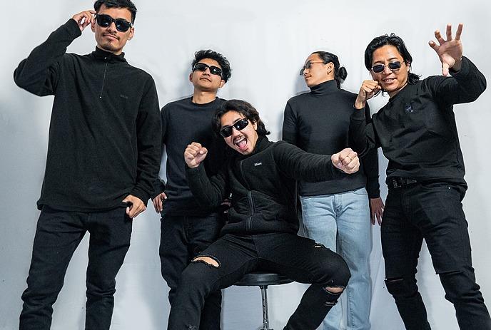Five band members in black outfits posing for a picture under a white