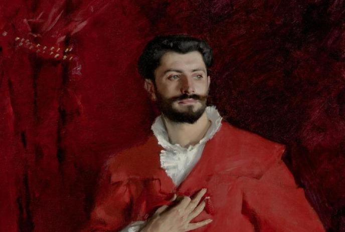Person in red with white-collared outfit, hand on chest, posing against deep red backdrop.