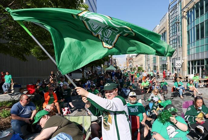 Group of people wearing London Knights merch at Dundas Place cheering and enjoying a game.