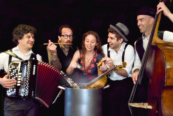 The band Schmaltz & Pepper happily stirring instruments like accordion, clarinet, violin, and bass into a big pot.