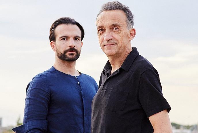 Justin Adams & Mauro Durante posing for the camera outside in front of a cloudy sky.