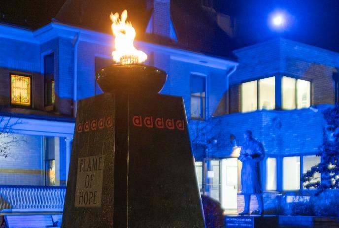 The Flame of Hope burning bright, with Banting House in the background under moonlight.