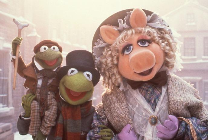 Kermit, Miss Piggy, and Robin in Victorian outfits on a snowy street from The Muppet Christmas Carol.