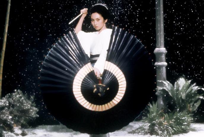 Person standing behind a black parasol with snow falling softly behind them.