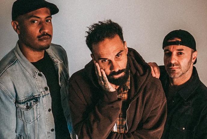 Letlive. band members stand together, viewed from above against a plain beige studio backdrop with calm, serious expressions.