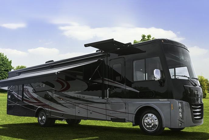 A large motorhome sits on a site with the awning out under blue skies.