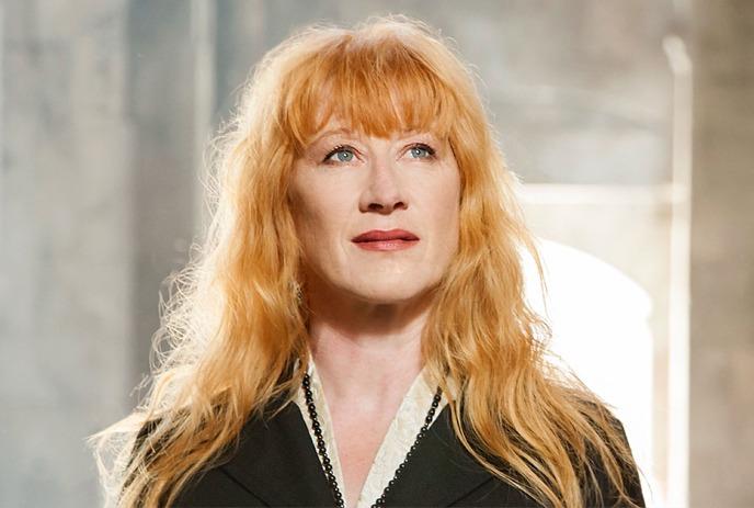 Loreena McKennitt playing a harp onstage with candles behind her.
