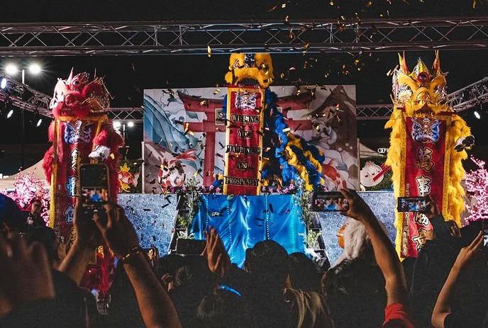 A glowing dragon costume dazzles the crowd, bathed in vibrant festival lights, alive with energy and celebration!