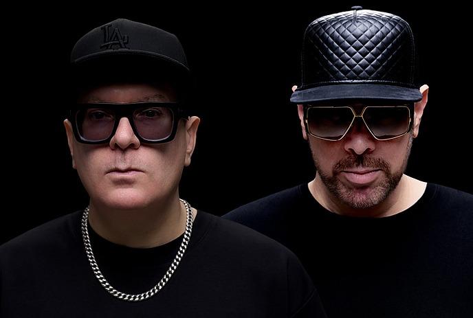 Headshots of Manzone & Strong, looking expressionless at the camera in front of a black background.