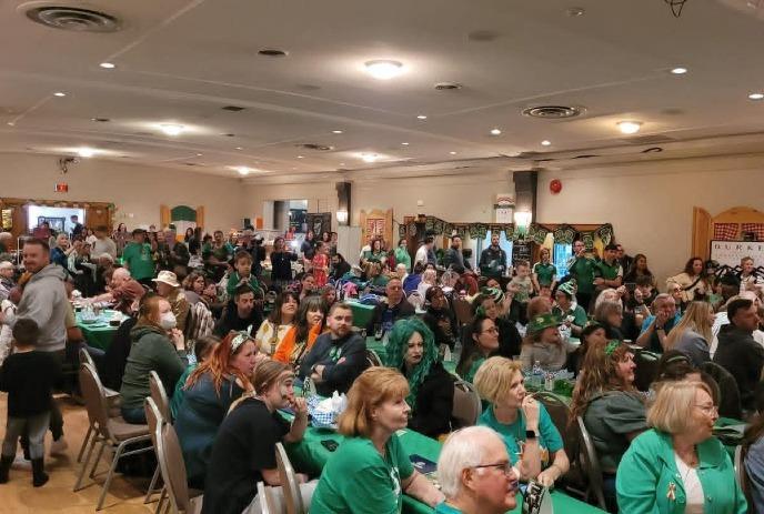 A large gathering of people in a hall celebrating St. Patrick's Day.