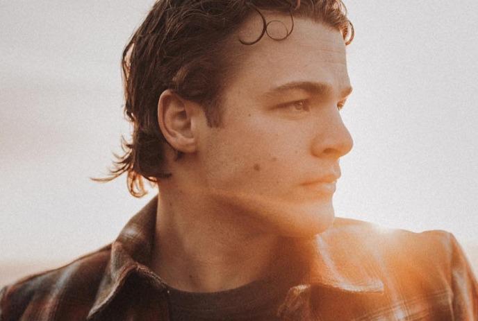 A headshot of Max McNown, looking sideways against a sunset.