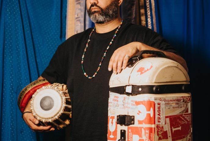 A person stands on a stage with items that enhance their musical storytelling presentation.