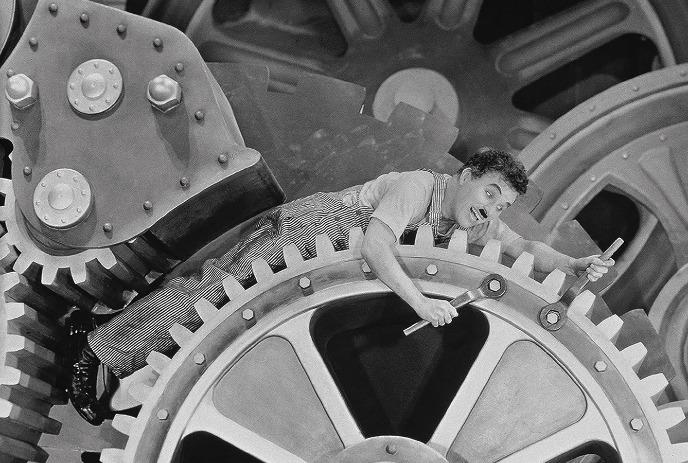 A person leans across a large gear n the inside of a clock.