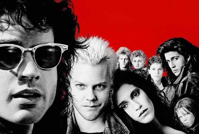 The Lost Boys stand together for a photo with a red background.