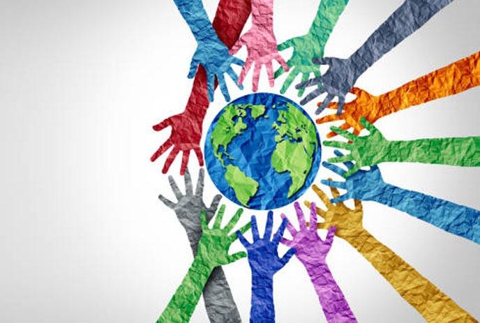 A group of colorful hands reaching towards a central globe with a white background.