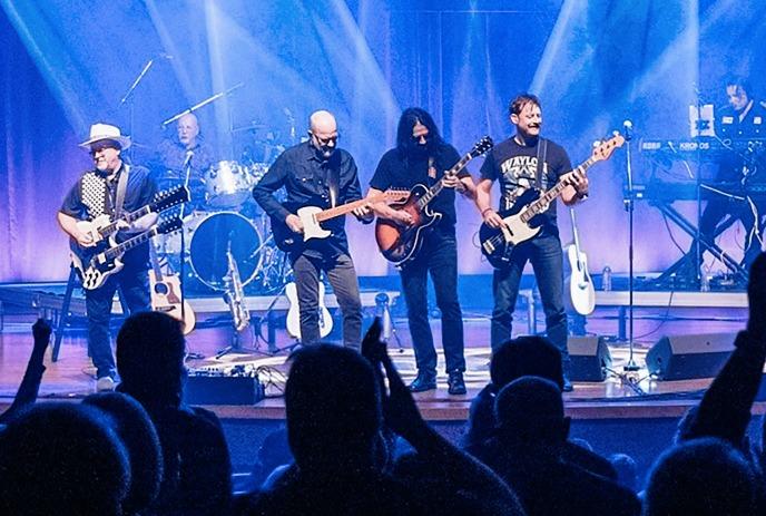 Band members on stage playing with purple lights in the background.