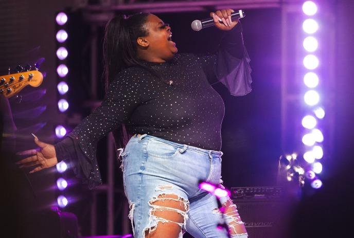 NESS singing on stage, with purple lights in the background.