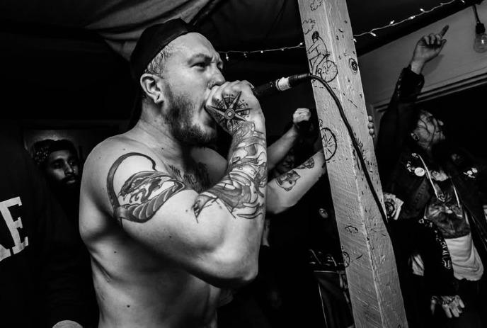 A tattoo-covered man singing into a microphone at a lively concert.