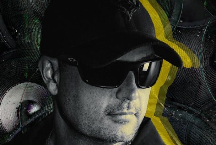 A close up headshot of Greg Gow, wearing a black hat and black sunglasses.