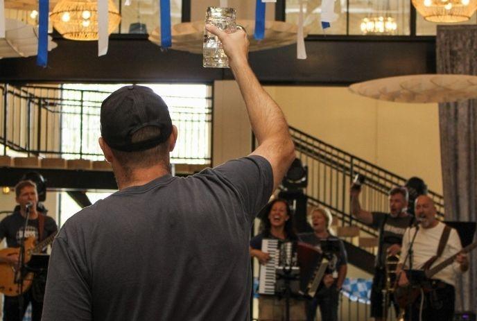 A person raises a glass towards musicians while making a toast.