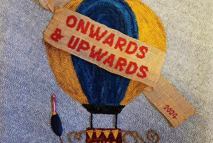 A rug design showing a hot air balloon wrapped in a ribbon saying 'Onwards & Upwards'