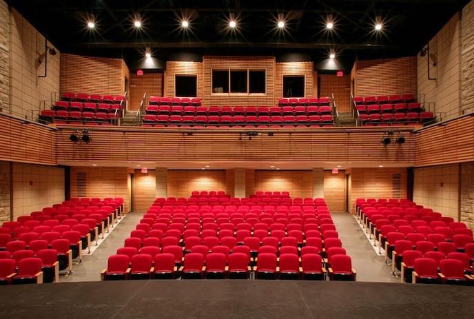 View from the stage to the theatre with red seats lining the orchestra and balcony.