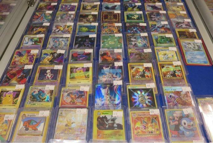 Display case filled with rows of sleeved Pokémon cards each priced and arranged neatly for collectors.