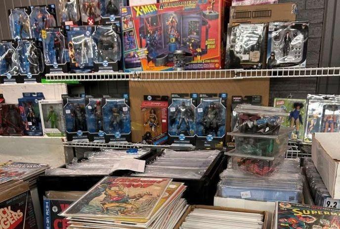 Shelves of boxed action figures above stacks of colorful comic books arranged neatly in a collector display.