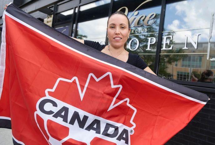 Diana Gutierrez, owner of Vice Supper Club, poses with a Soccer Canada flag outside her restaurant in London.