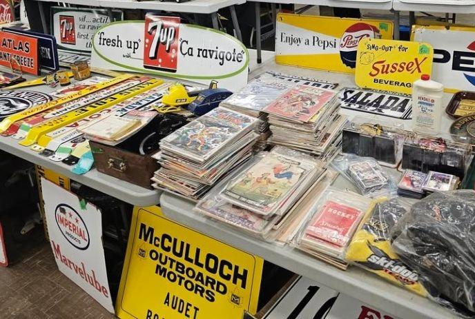 Table filled with colorful retro signs comics cards and small collectibles arranged together at a market display.