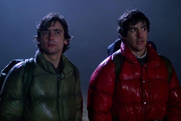 Two young people stand together in the cold, dark evening looking afraid.
