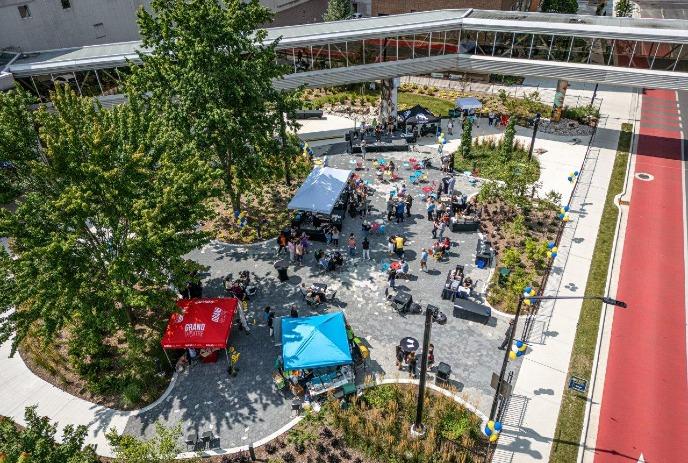 An overhead, sunny view captures crowds gathering around tents and a stage at the Encore Terrace outside RBC Place London.