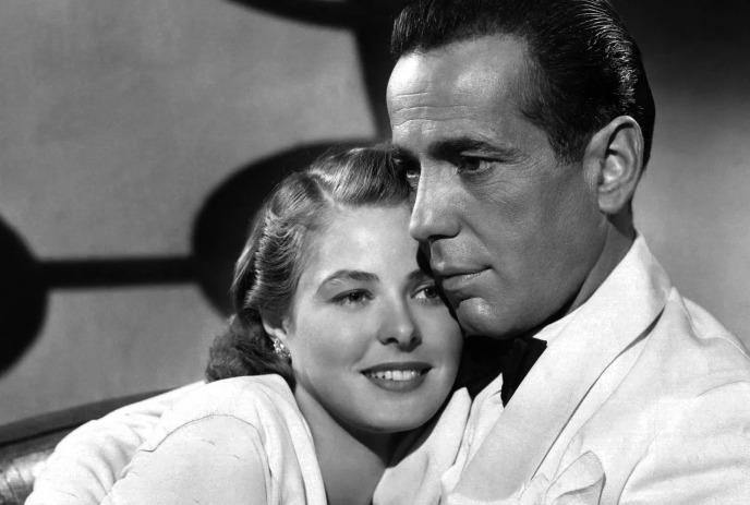 Black-and-white film moment: man in tuxedo with a women smiling on her shoulder.